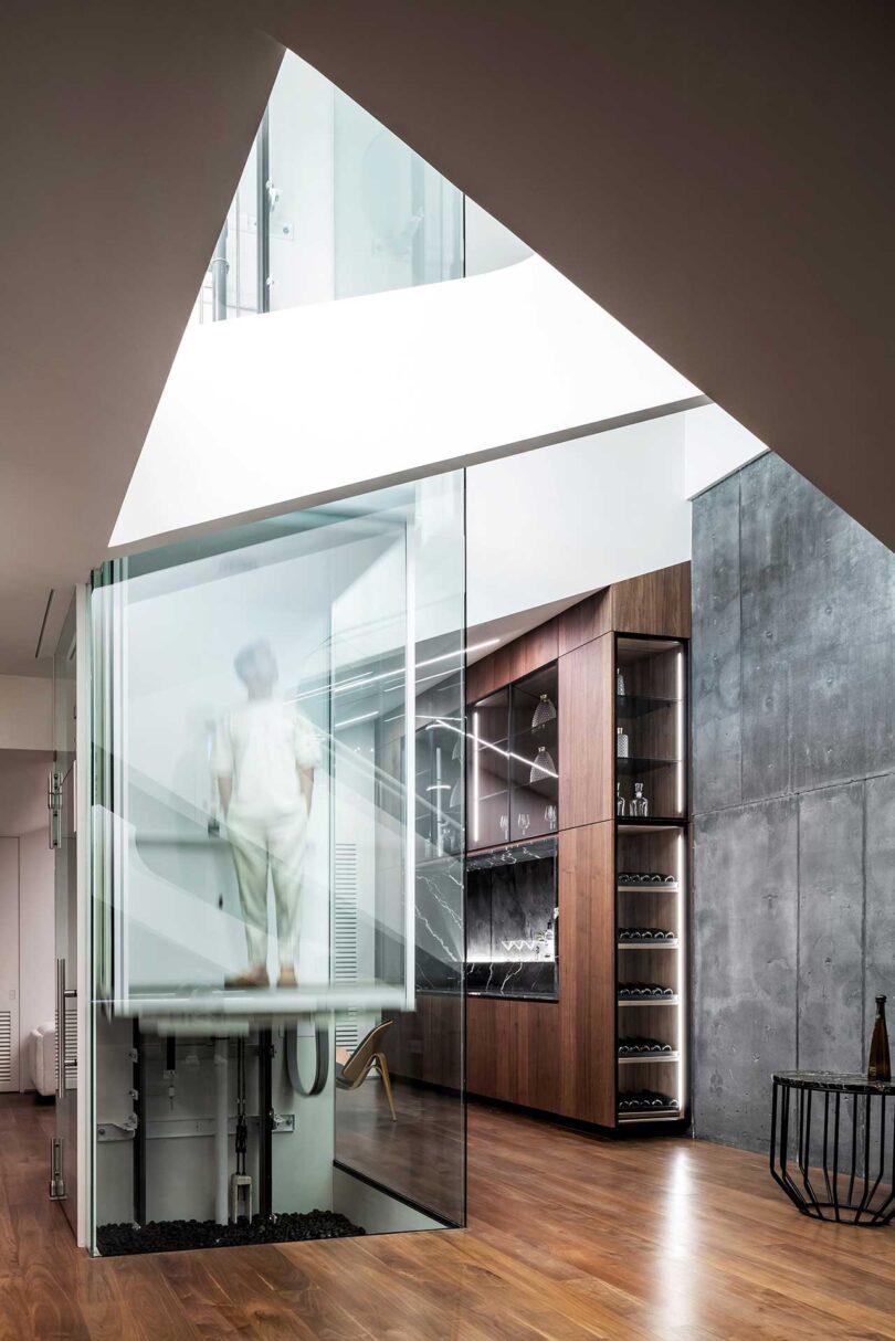 partial interior view of modern living space with glass elevator holding man