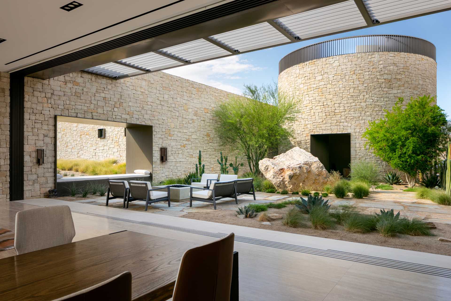 A modern home with a fully-enclosed, shaded courtyard area that's been designed for family meals and gatherings. 
