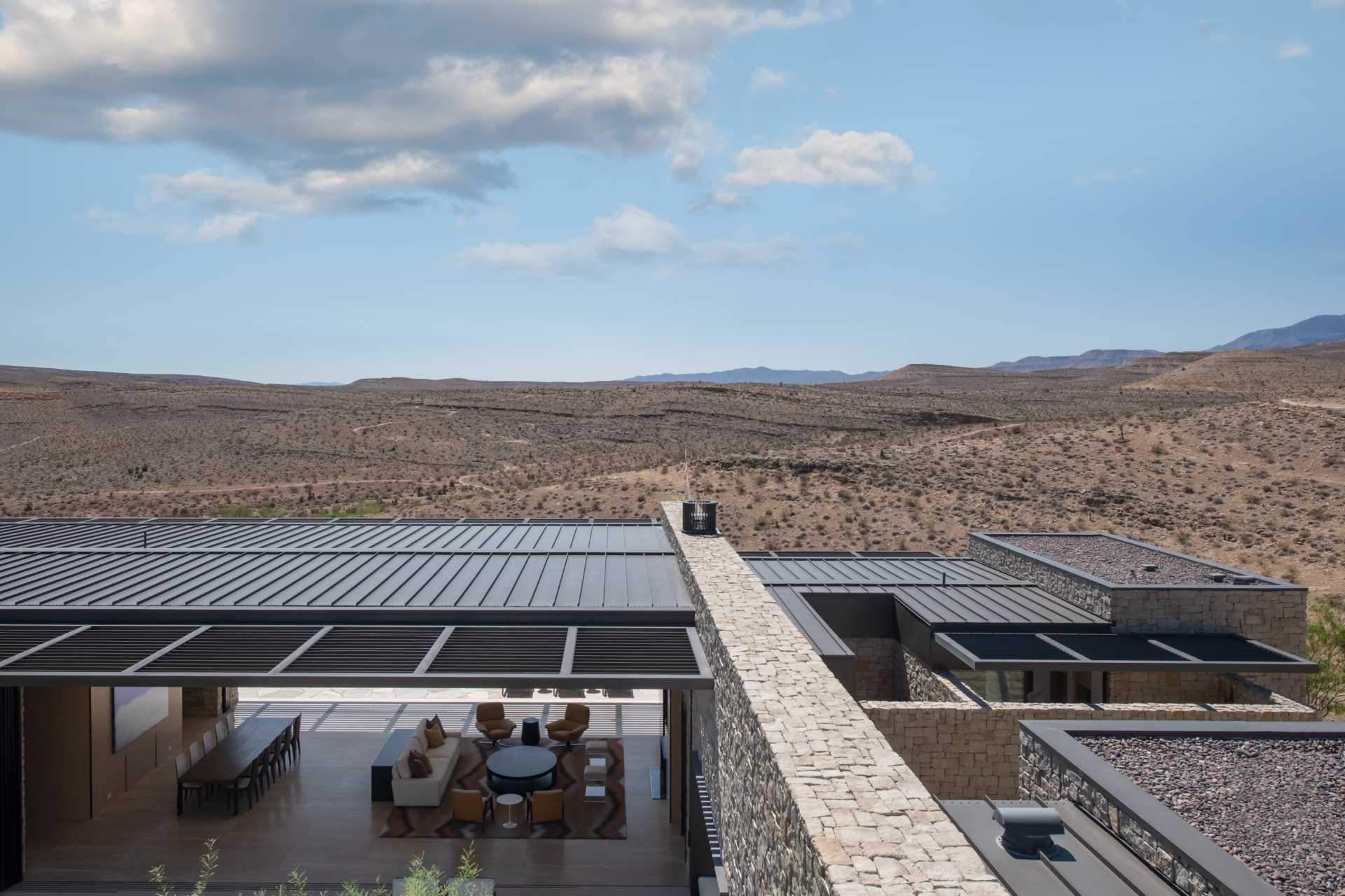 A modern home in the desert features weathered and hot rolled steel, stone walls, sliding glass panel walls, and travertine.