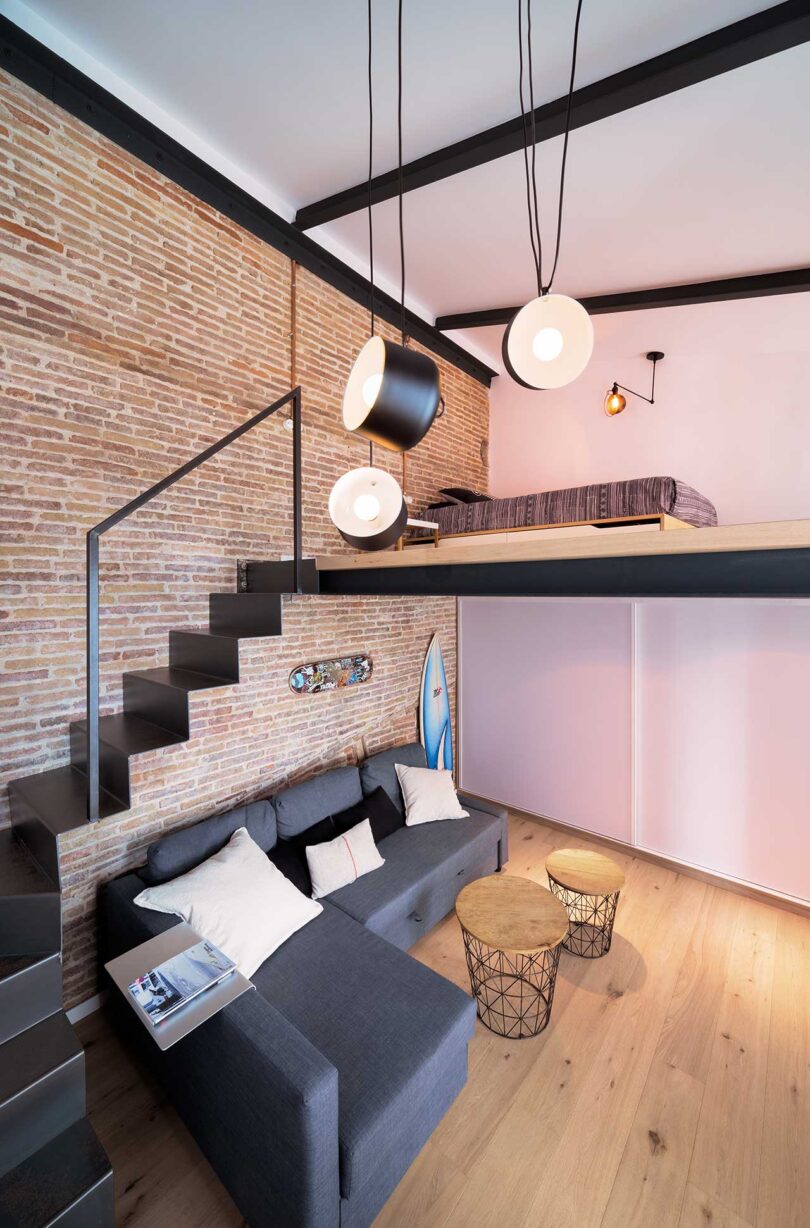 interior view of modern living space with small sectional sofa underneath loft bed with stairs wrapping around