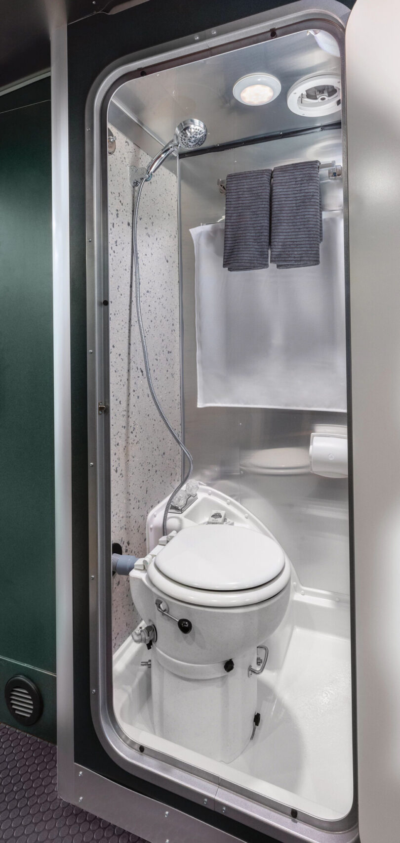 Door open to the water-saving composting toilet and bathroom with shower overhead.