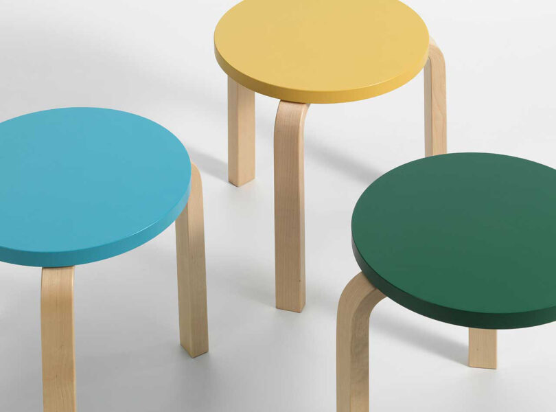 three stacked stools in dark green, yellow, and light blue on a bright yellow floor