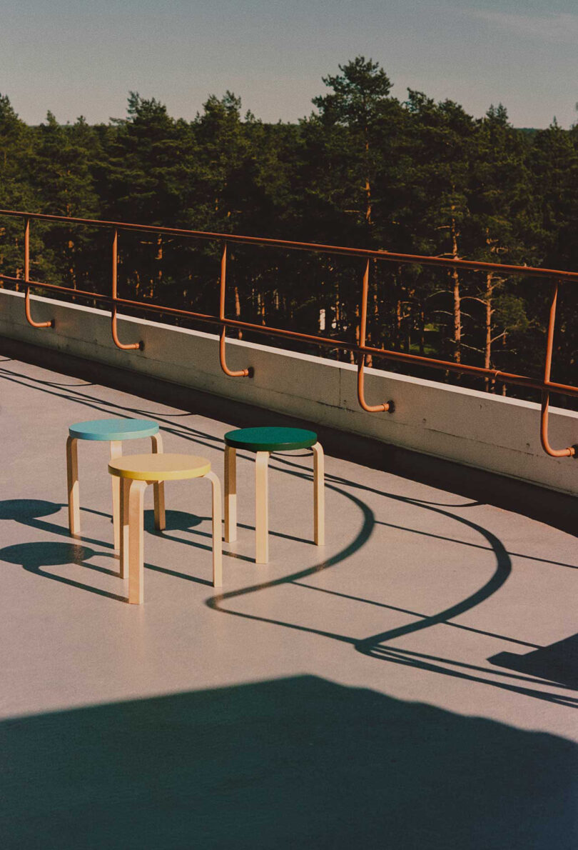 three stools in dark green, yellow, and light blue floor on the rooftop of a building