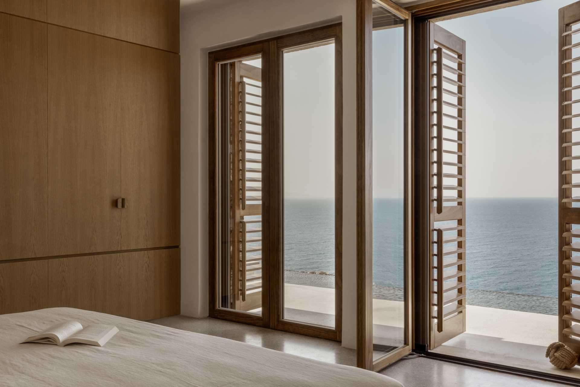 A modern bedroom with windows that open to a sea view.