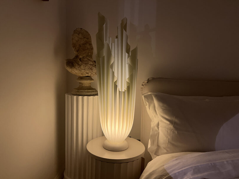 an illuminated column table lamp with frilled edges in a styled space