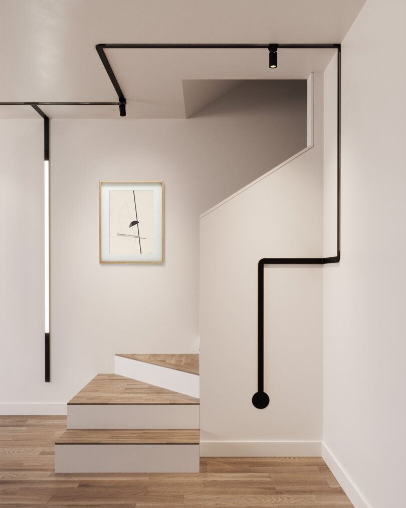 Off-white room with small angled staircase framed by a bending length of Juniper MULTIVERSE ribbon tracks in black, with long ambient light module to the left following down one side of the wall and a small spotlight on the ceiling.