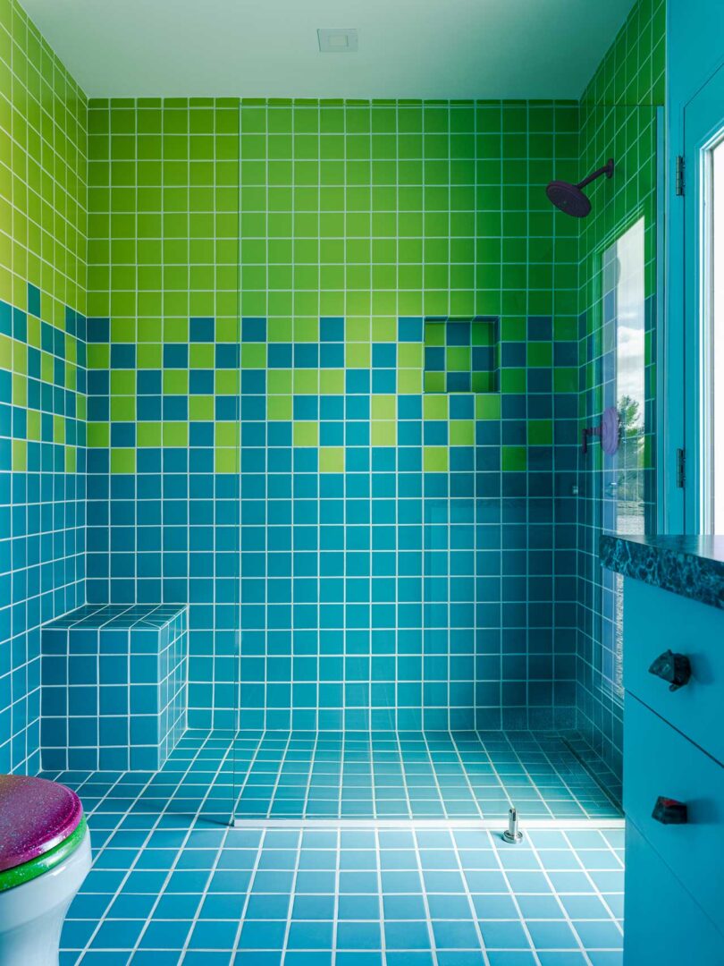 shot of modern bathroom with bright green and turquoise mosaic tiles in shower