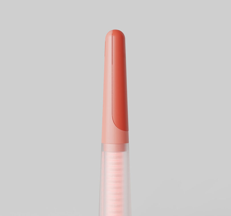 Detail of the coral red toothbrush with its magnetic plastic brush cover fully placed over bristles.