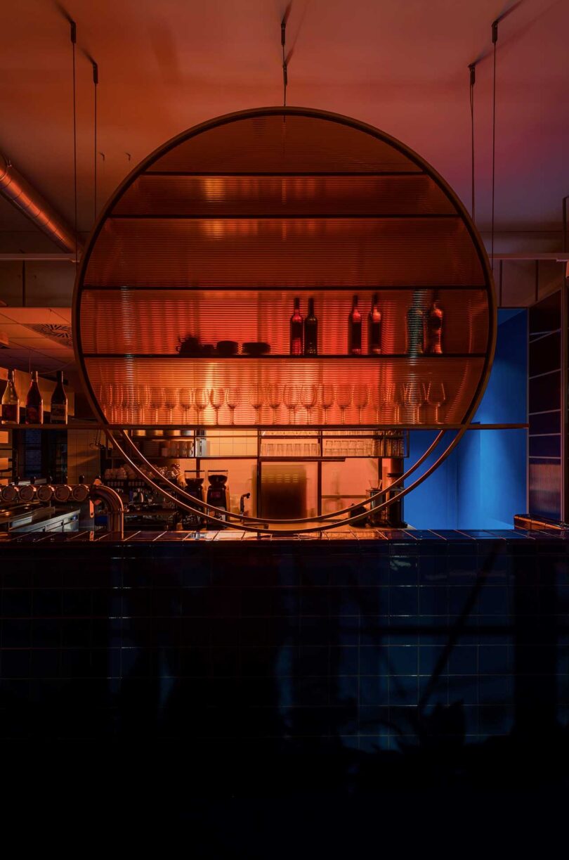 nighttime view of cafe interior with glass circular shelf that has peach and pink glowy lights filtering through