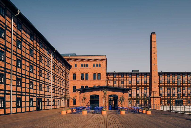 exterior shot of brick industrial building with blue chairs on patio