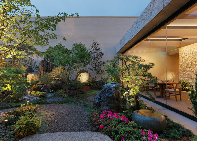 Japanese rock garden landscaped with California native plants illuminated at dusk with dining area to the right.
