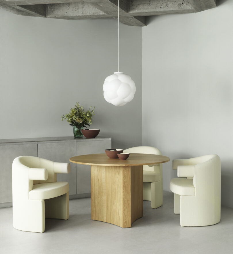 two white dining armchairs at a round table in a styled space
