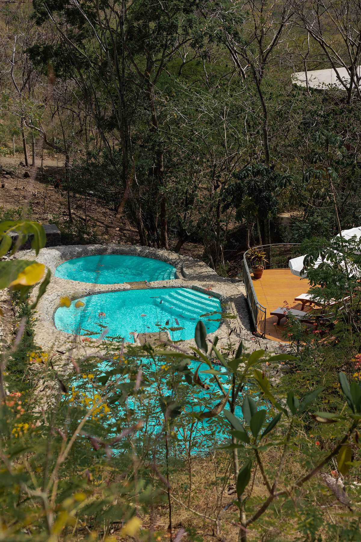 These swimming pools each have a round shape and are tiered allowing the water to flow between them.