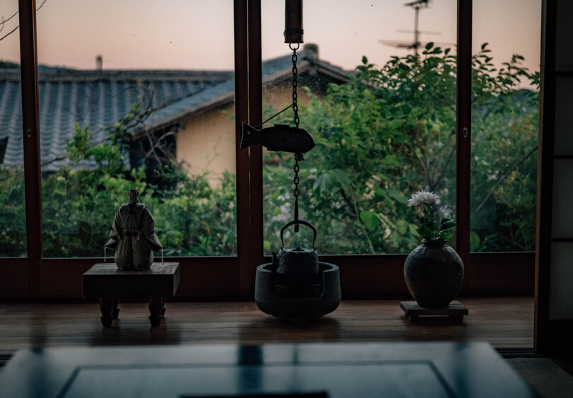 Detail shot of traditional Japanese hanging teapot, with garden views in the background. 