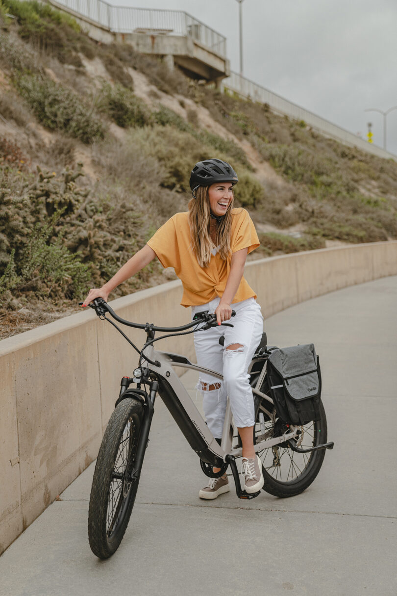 light-skinned woman sitting on a cream colored e-bike on a road