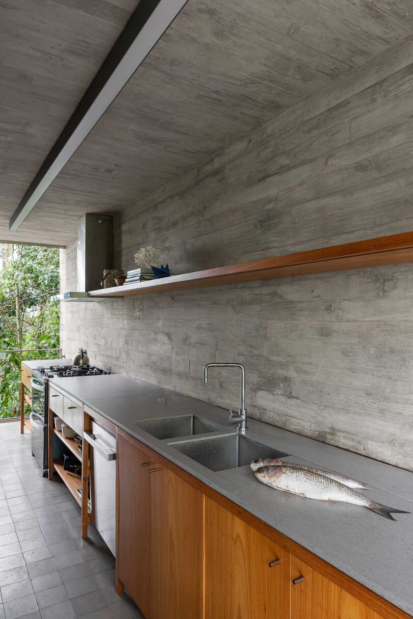 angled view of modern minimalist kitchen with concrete wall and lower wood cabinets
