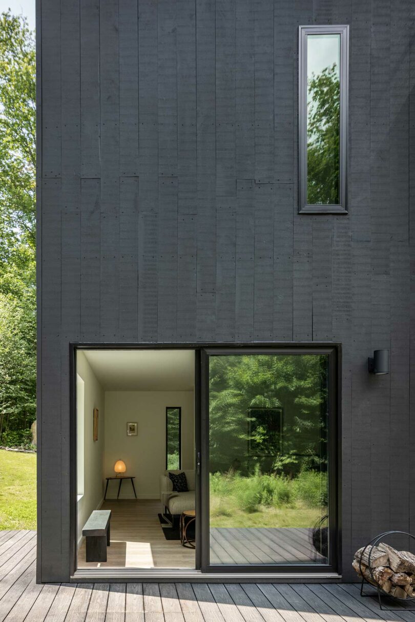 closeup corner view of modern black box house surrounded by trees
