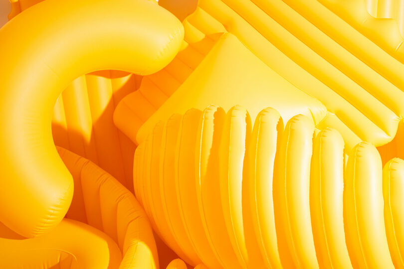 closeup of a bunch of yellow oversized pool floats shaped like pasta