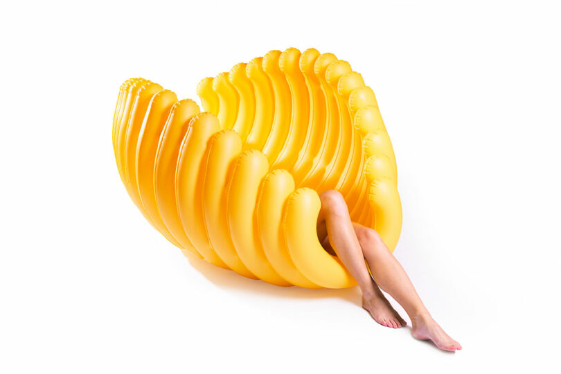 large yellow shell-like pool float with person's legs sticking out at end