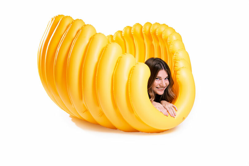 large yellow pasta shell shaped pool float with woman's head sticking out end