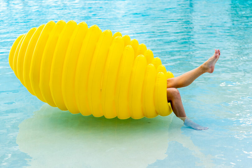 large oval ribbed pool float with legs sticking out one side while floating in pool