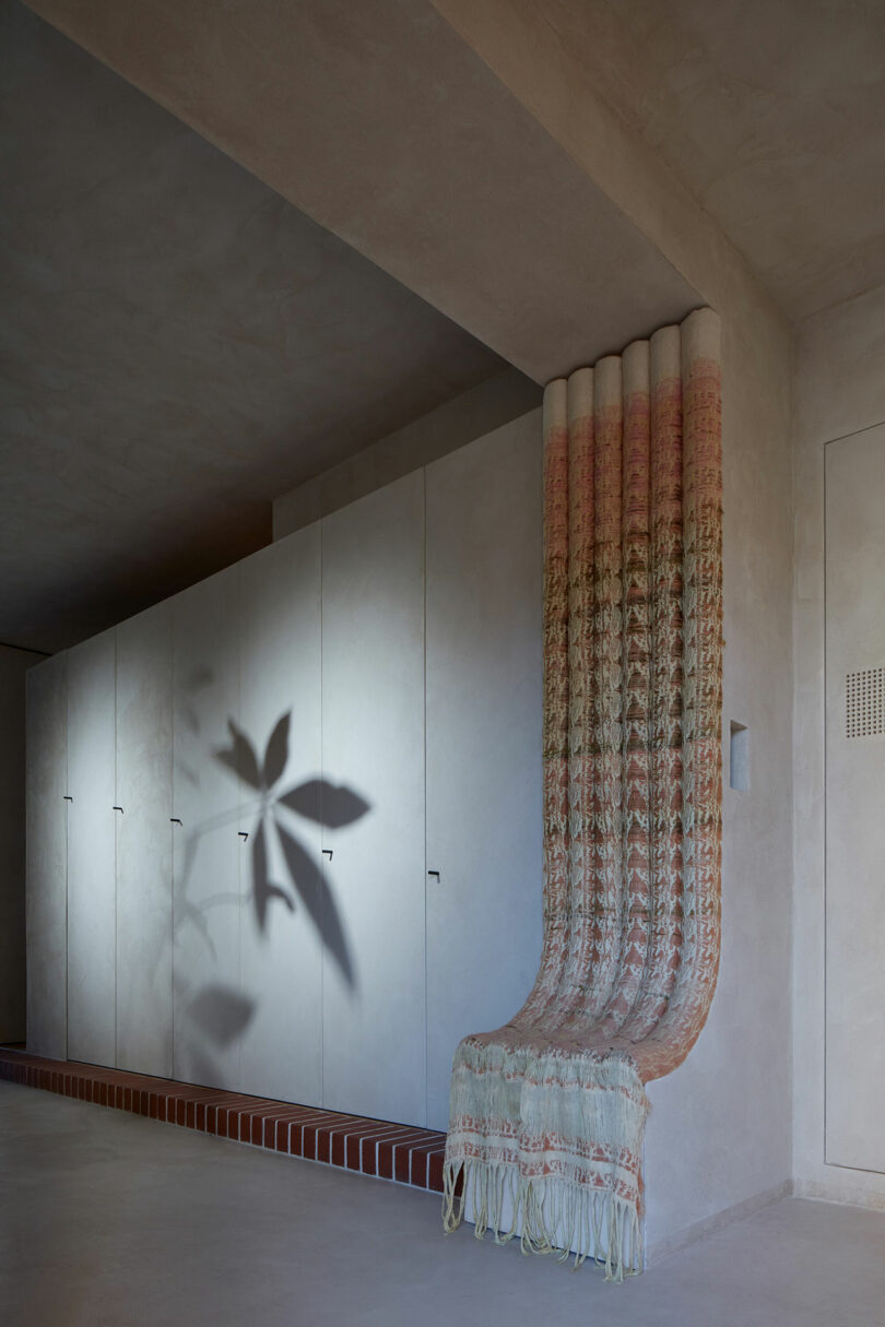 angled partial view of hallway in modern apartment with beam adorned with textiles