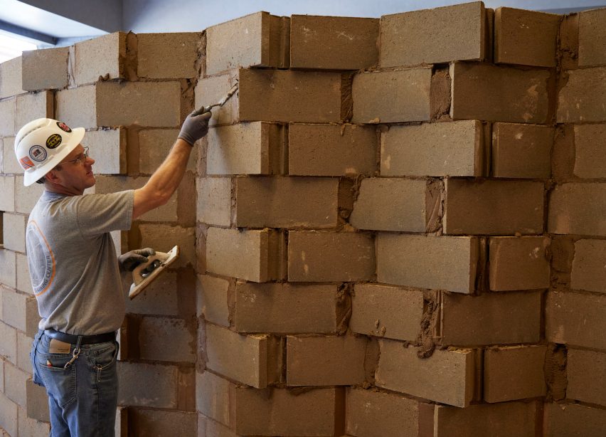 A person installing a sculpture of bricks