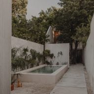 Concrete courtyard with a small swimming pool, concrete perimeter walls and lush green trees