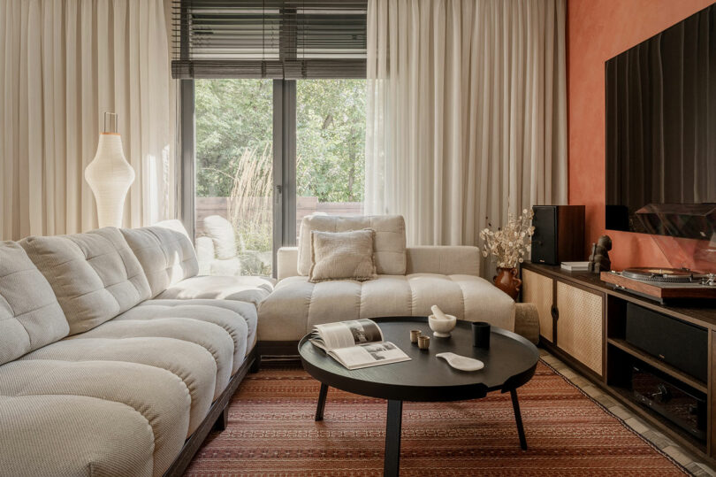 modern living room with ribbed white sofa and orange statement wall behind tv