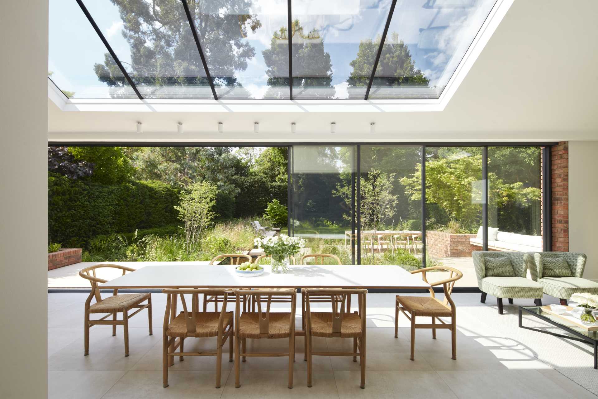 A casual living room with built-in cabinets and shelving, has a view of the light-filled addition and the garden beyond.