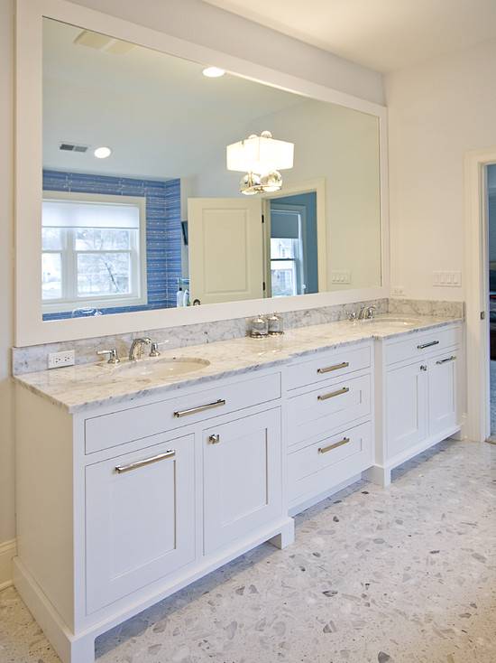 White double vanity with white marble countertop. Terrazzo flooring, double wide framed mirror with Global Views "Fortune Teller" sconce from Horchow.