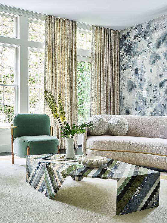 Contemporary living room features a green, black and gray lacquered coffee table with a gold and green chair, cream sofa and black and white accent wall.