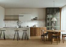 A large mid-century kitchen with an island and stools close to a round table with chairs.