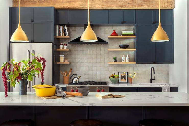 Three gold Aerin Agnes Pendants hang over a marble-look countertop accenting a black center island in a well appointed black kitchen.