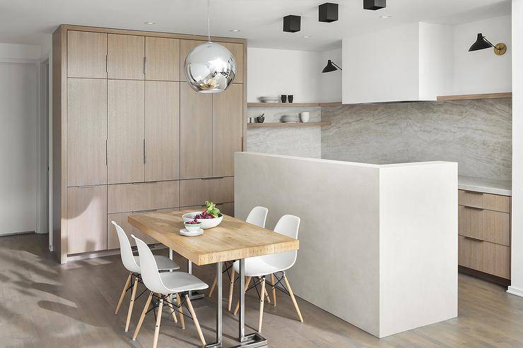 Modern eat-in kitchen features white molded plastic chairs placed at a wood and metal industrial table lit by a Eugene pendant.