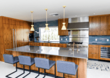 Dark cabinetry mid century modern kitchen with wood finishes, navy blue chairs, and navy blue accents.