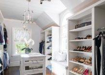 Sun-filled walk-in closet boasts a white closet island adorned with mirrored drawers and topped with marble. A built-in closet window seat is flanked by tall shoe shelves.