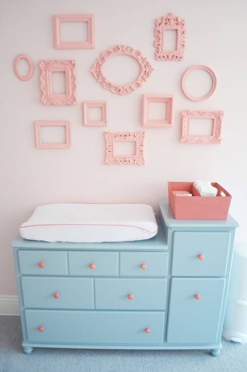 Pink and aqua blue nursery with changing table painted blue, Sherwin Williams Interesting Aqua, adorned with pink hardware below walls painted pink, Sherwin Williams Armour Pink, accented with a gallery wall of empty frames painted Sherwin Williams Hopeful.