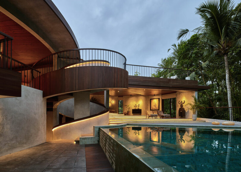 exterior evening view of modern concrete and wood house with spiral design and swimming pool