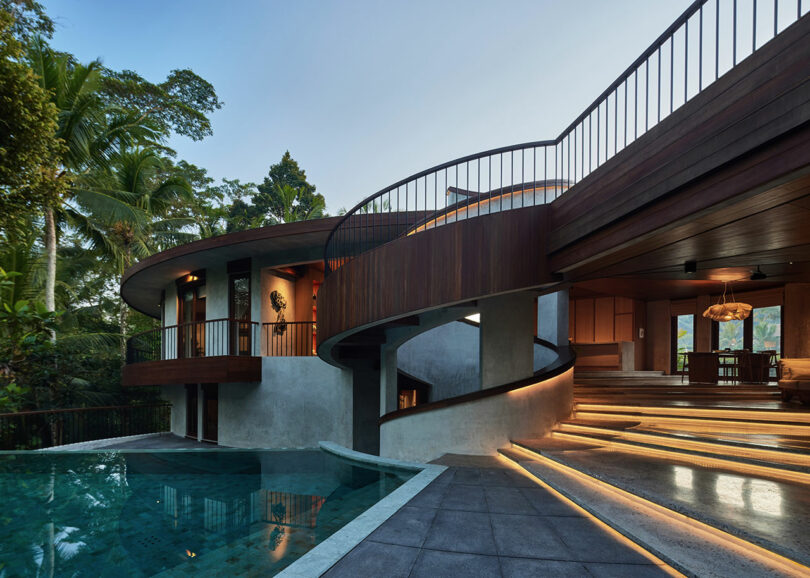 exterior evening view of modern concrete and wood house with spiral design and swimming pool