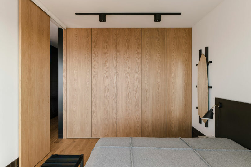 side view of modern minimalist bedroom with wood wall and simple bedding
