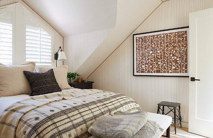 Bedroom features a queen bed in front of shuttered windows and brown art on brown striped wallpaper.