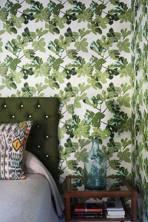 Peter Dunham Fig Leaf wallpaper covers the walls of this beautiful green bedding featuring a bed with a green tufted headboard.