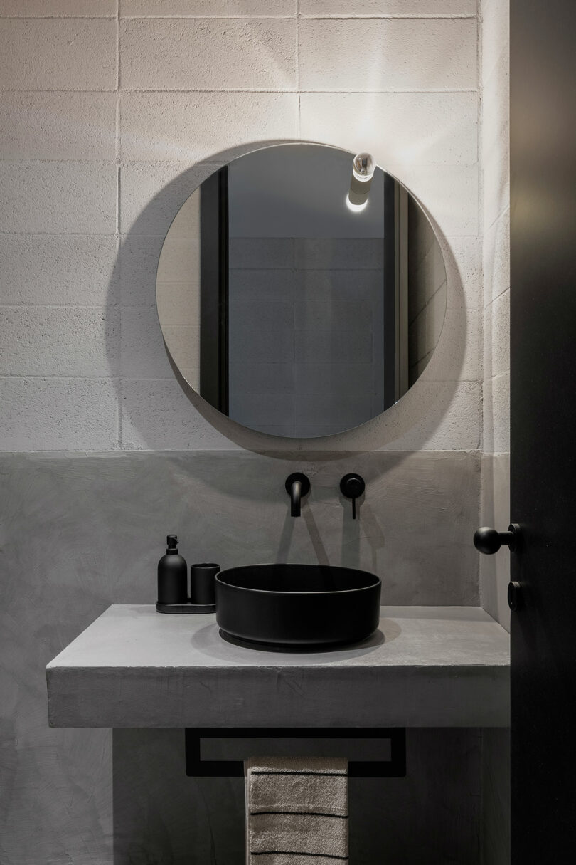 modern industrial bathroom with gray concrete counter and black sink