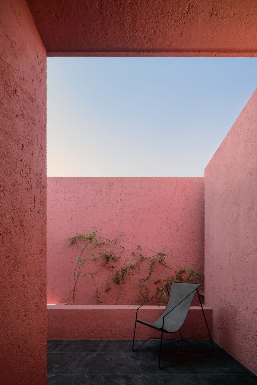 Enclosed balcony with pink walls and a single black chair
