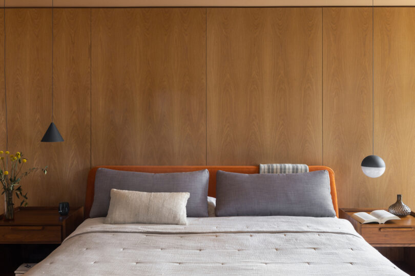 bed with three pillows on it in wood paneled room