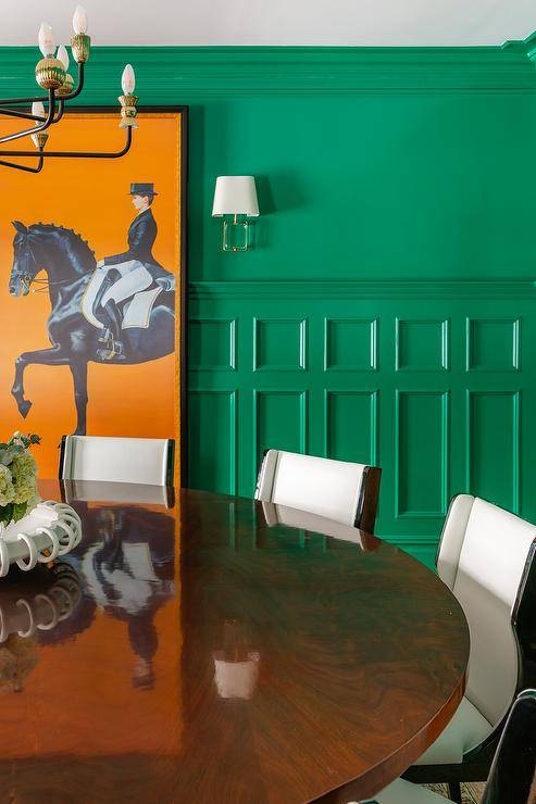 Hermes orange art hangs from a green wainscot dining room wall.