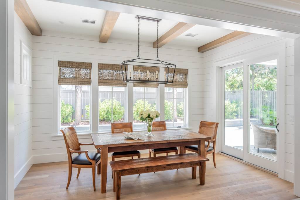 A dining room with white shiplap, a wooden table and chairs.
A dining room with white shiplap, a wooden table and chairs.