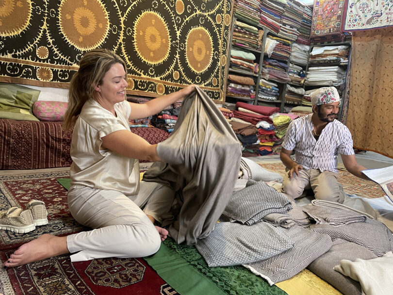 a man and woman sort through a pile of colorful textiles