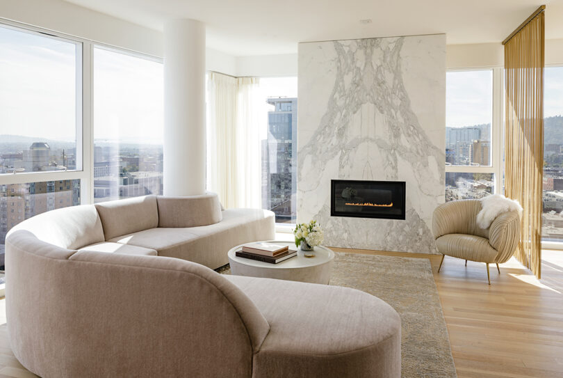 light and bright styled interior space with curved sofa and marble fireplace